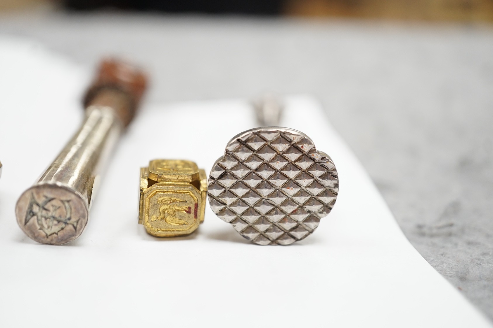 A group of twenty-five steel, gilt metal or nickel fob or desk seals, mostly 19th-century, including a steel swivel seal, a seal with boxwood finial modelled as a hand holding a ball and a nickel multi seal